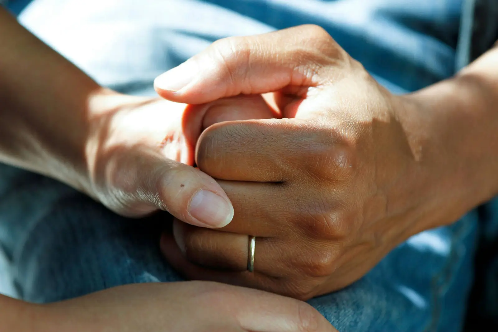 A caregiver gently holding an older adult's hand